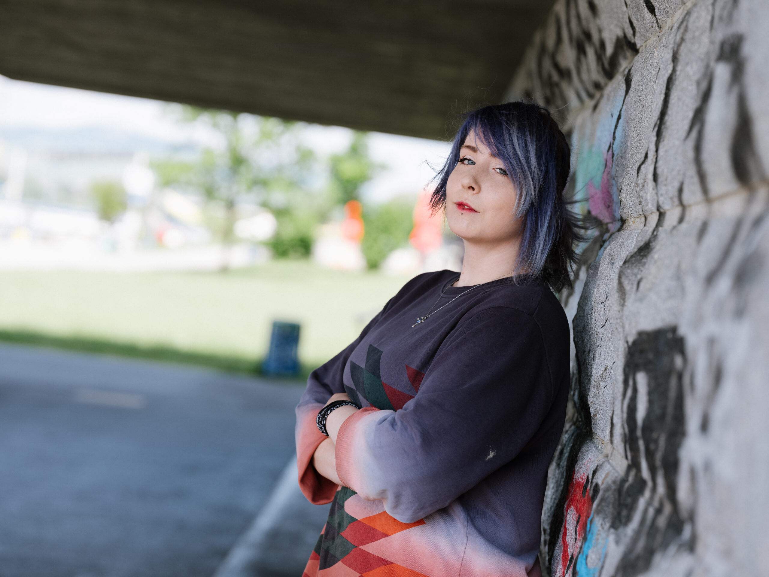 junge Frau mit lehnt an einer mit Graffiti besprühten Wand